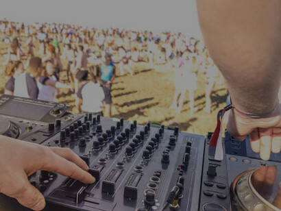 Outdoor beach party at sunset with a DJ playing live music and summer fun