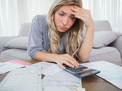 A young woman sits in deep thought, worried about mounting debt and rising taxes