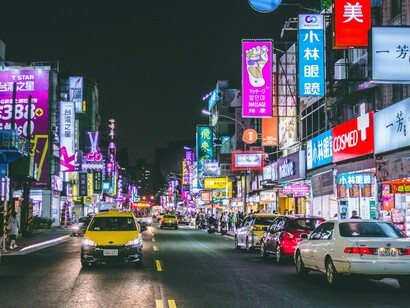 A vivid night view of Hong Kong streets filled with vehicles, lights, and pedestrians, capturing the flow of everyday city life
