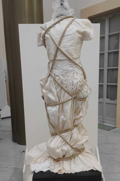 L'abito da sposa, donato ad Indaco Donna, è costretto da una corda che stringe il corpo privando il corpo di libertà di movimento