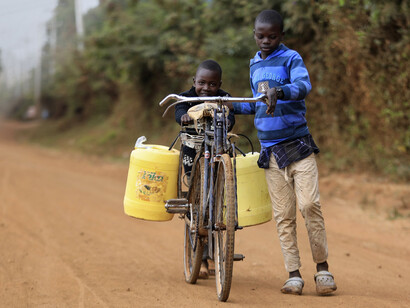Niños africanos transportan agua potable en una bicicleta