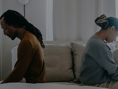 In a scene of shared unease, a couple sits together on a bed, underscoring the pivotal significance of clear and compassionate communication in bridging emotional gaps and fostering a healthier, more connected relationship
