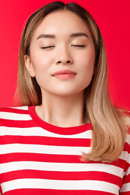 A young woman practicing meditation and deep breathing against a red background for stress relief and relaxation