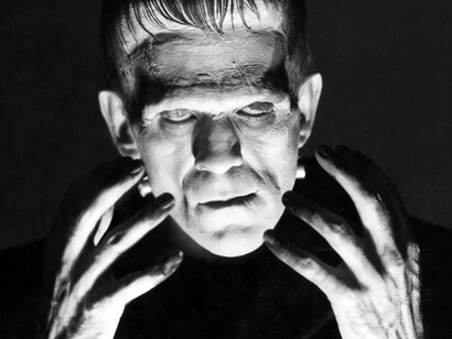 The monster that Frankenstein created looks like he is ready to demolish a being or a structure as his monstrous hand are raised 