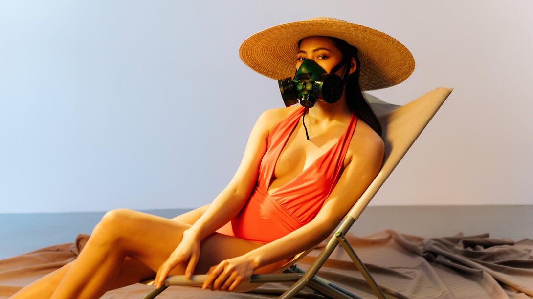 Mulher usa respirador na praia pois o ar está contaminado