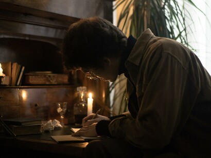 A young man busy handwriting at his desk, the old fashion way, with paper and pen