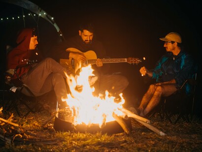 Friends gathered around a campfire and singing, representing the kind of culture that is lived together rather than performed for an audience