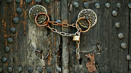 A heavy chain binding the handles of an old wooden door, illustrating the persistent diplomatic stalemate between Morocco and Algeria