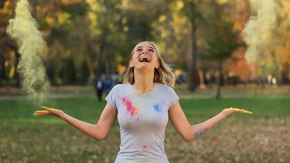 A joyful woman celebrating by playfully tossing powdered color