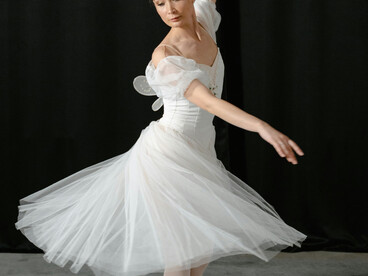 Ballet dancer in a flowing white dress performing on stage