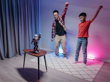 A father and son dancing together while watching a robot
