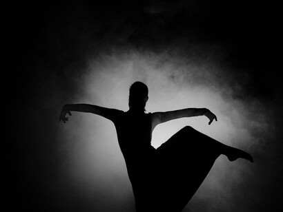 Um bailarino surge da escuridão, recortado pela luz como se o movimento pudesse revelar aquilo que permanece invisível. Para a autora, criar é justamente uma forma de dar expressão à força vital que existe dentro de nós. Às vezes, basta uma fresta de luz para que aquilo que vive dentro de nós encontre passagem