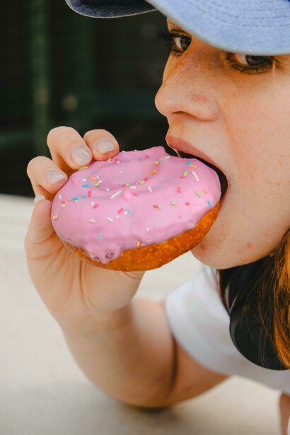 Close-up of a woman eating a donut, illustrating sugar overload, sugary snacks, and junk food addiction