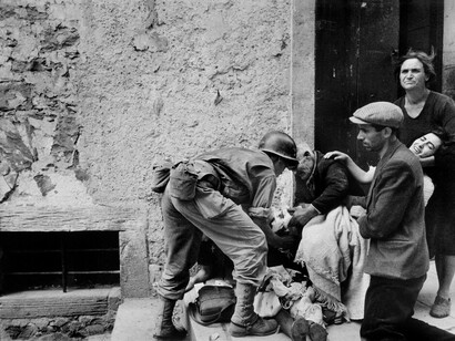 Un soldato americano aiuta ad assistere una donna ferita. Nicosia, luglio 1943. © Robert Capa © International Center of Photography/Magnum Photos