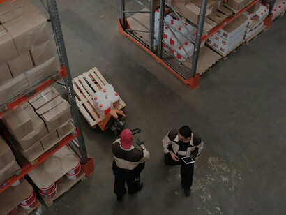 In a vast warehouse, men diligently operate a pallet truck, seamlessly navigating through the space with skill and efficiency