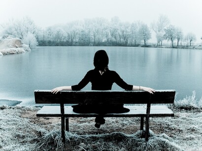 Una mujer contempla un lago desde un banco
