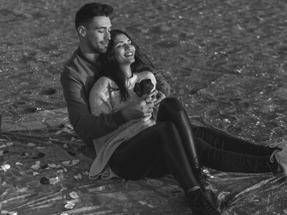 A couple lost in conversation and affection on the beach, reminiscing about their past connection and enjoying a romantic evening