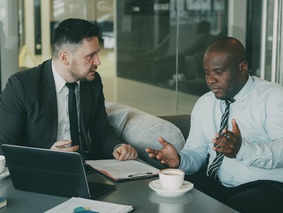 Two business professionals discussing plans and documents, symbolising informed guidance as part of a stronger workplace benefits strategy