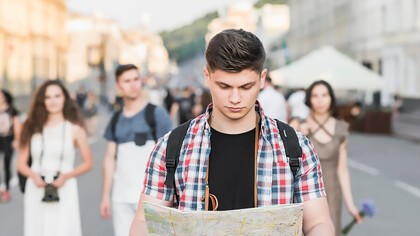 International student navigating academic migration while walking on the street with a map
