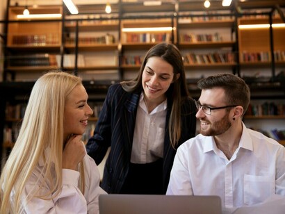 Colleagues collaborating and studying in a library, using laptops to explore innovation, the knowledge-based economy, digital transformation, and the role of technology in driving progress