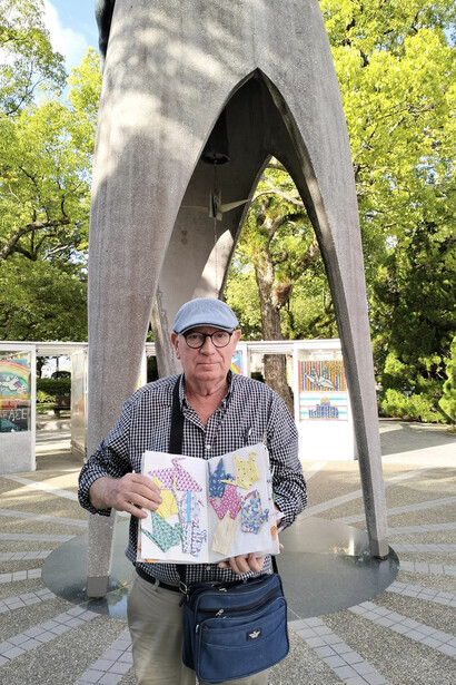 El autor presenta el álbum con grullas de origami en el monumento a Sadako del Parque de la Paz, Hiroshima