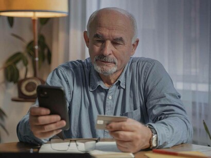 A man entering his credit card information via smartphone as his way of stating he's in the silver economy