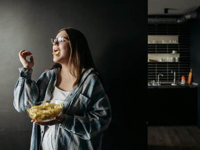 A woman standing with a bowl of chips, reflecting an imperfect, snack-based meal