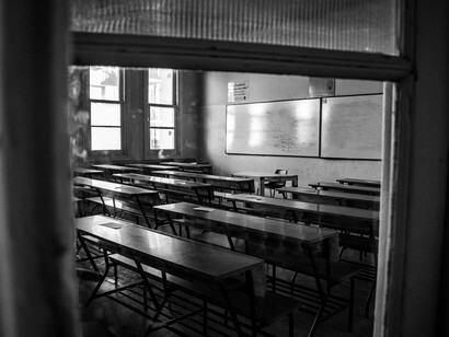An empty classroom with rows of vacant desks, representing the lasting impact that violence leaves on learning environments