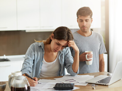 A young couple sits together, checking their family budget and expenses