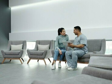 A patient reviewing information with a healthcare professional in a waiting area, representing the human impact of delayed access to care