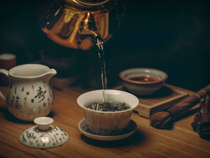 A golden kettle pours hot water into a teacup, capturing the art of tea brewing