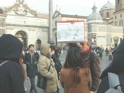 Alberto Tagliaferri a Piazza del Popolo, mentre mantiene un diagramma che mostra la chiesa di Santa Maria del Popolo e spiega la storia della zona dal 1600 