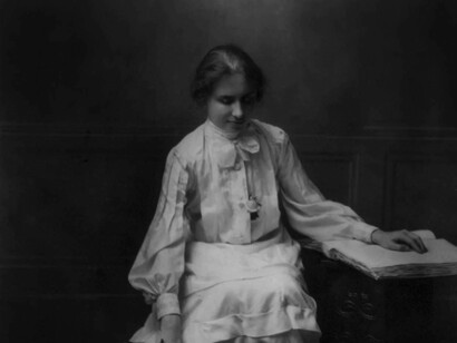 A young Helen Keller reading brail in her bedroom