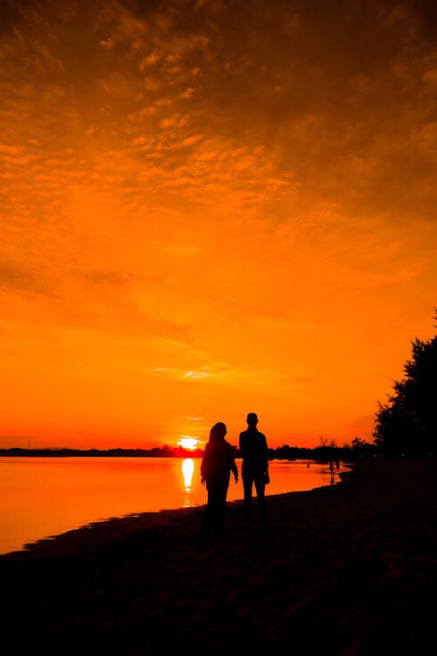 Amidst the hues of a fiery sunset, they walk together, knowing that even in the midst of uncertainty, their love is a beacon guiding them through life's tumultuous seas