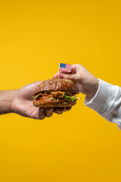 Mani che si passano un hamburger, piatto tipico americano 