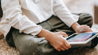 Mãoszinhas manuseiam tablet enquanto brinca com jogo