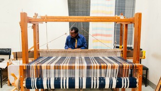 Tecelão artesanal. A produção artesanal é, por natureza, mais lenta e limitada em quantidade, o que reduz a pressão sobre os recursos naturais. Esta abordagem slow fashion contrasta fortemente com a mentalidade de fast fashion, incentivando os consumidores a valorizar mais cada peça de roupa, em vez de comprar e descartar rapidamente. É um convite à reflexão sobre o verdadeiro valor das roupas e a história que cada fio carrega
