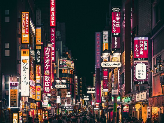 Night view of a busy street in Shinjuku, Tokyo, illuminated by vibrant neon signs and crowds of pedestrians, Japan