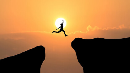 A courageous man leaps through the gap between hills