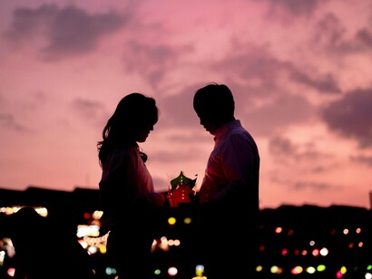 A couple cradling a glowing lantern beneath the evening sky, representing hope carried through years of waiting and sacrifice
