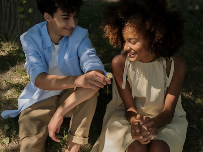 On their inaugural date, a young boy and girl leisurely walk through the park, exchanging smiles, finding a quiet spot to sit, and weaving the beginnings of a delightful connection