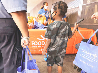 A young child watches as people pick up food items during Food Bank for New York City’s 5 Borough Pop-up in Brooklyn, New York, USA