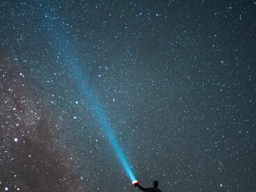 Sob a imensidão do universo, uma pequena luz humana rompe a escuridão. A literatura também nasce desse impulso de iluminar o desconhecido