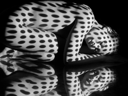 The nude woman painted with black and white zebra stripes embodies the contrast of darkness and light, explores human connection, and evokes surrealism