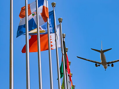 Flags flutter in front of the United Nations headquarters as a plane soars gracefully above the symbol-laden scene