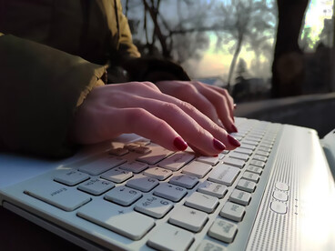 A person is actively typing on a laptop, immersed in their task
