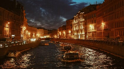 Illuminated buildings lining the Fontanka River at twilight in Saint Petersburg, Russia, representing the beauty and complexity the author discovered beyond the familiar Russian postcard