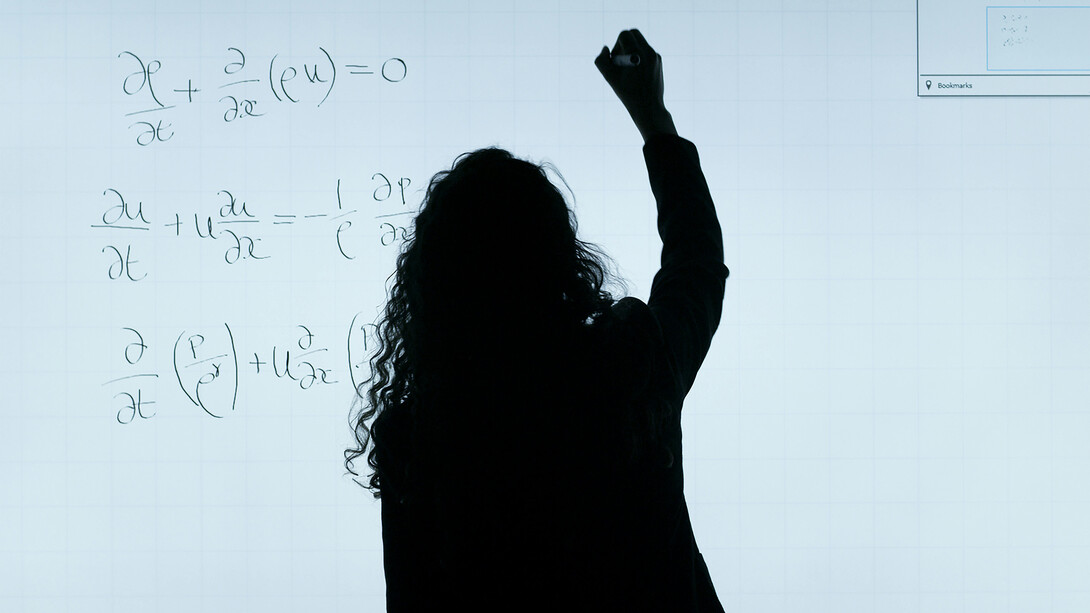 A woman writing on a whiteboard during a university lecture