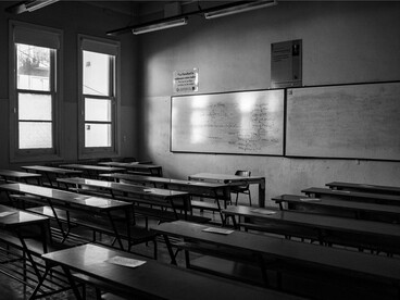 An unoccupied classroom filled with empty desks, reflecting the importance of investing in mental health and student support