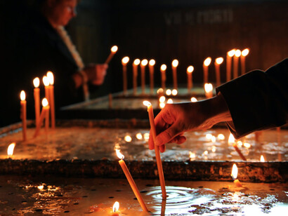 Una donna accende delle candele in una chiesa